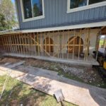 Florida Hauling & Demo CAT mini excavator working on a home addition with the first-floor exterior opened to framing